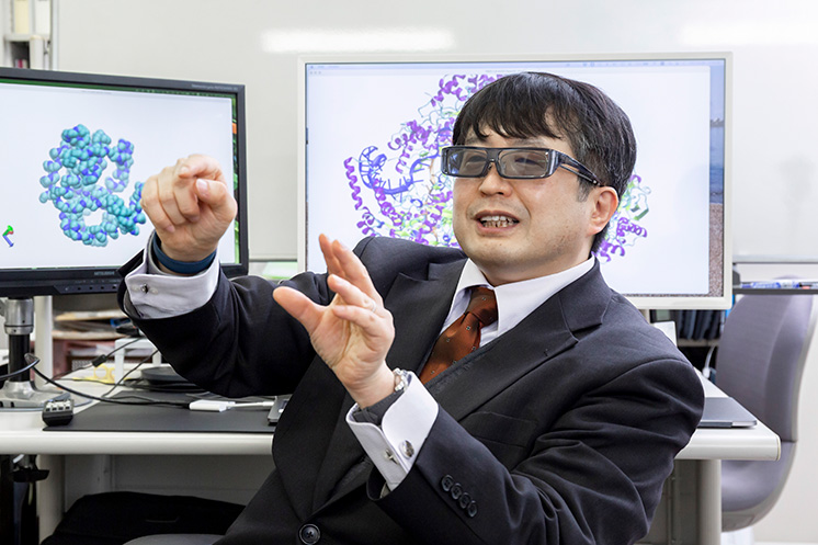 写真左側のディスプレイに表示されているタンパク質構造のモデルは3D化されており、3Dメガネを使うと立体的に見える